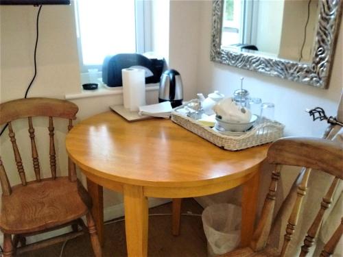 een houten eettafel met stoelen en een spiegel bij Sunny Patch in Stroud