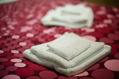 drei weiße Handtücher auf einem roten und weißen Tisch in der Unterkunft Posada de Liz y Fabrizio in Rom