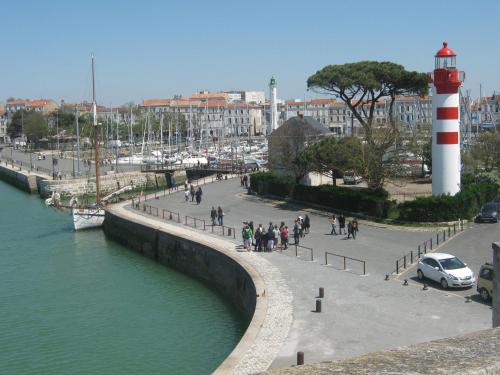 a group of people walking on a pier next to a lighthouse at Hotel La Marine, Vieux Port in La Rochelle