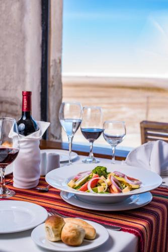 a table with a plate of food and wine glasses at Hotel de Sal Luna Salada in Colchani