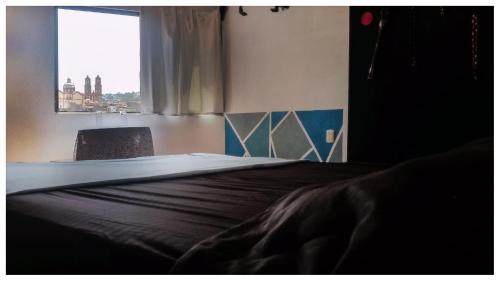 a bedroom with a bed with a window and a chair at Taxco de mis amores in Taxco de Alarcón