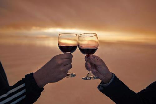 two people holding up two glasses of wine at Hotel de Sal Luna Salada in Colchani