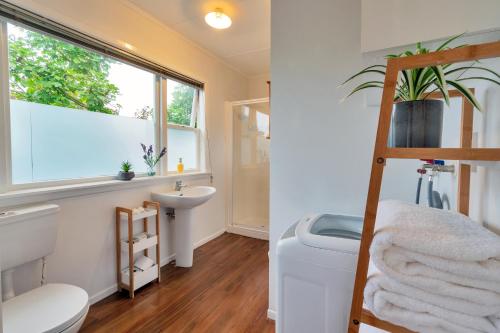 uma casa de banho com um lavatório e uma janela. em Sunny & Cozy Home near Western Springs em Auckland