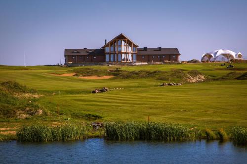 a house on top of a hill next to a body of water at Gorki Golf Resort in Gorki