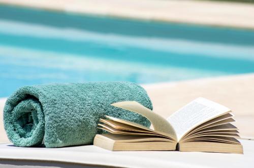an open book and a towel on a table next to a pool at En Plo Boutique Suites in Oia