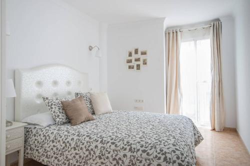 a white bedroom with a bed and a window at Chez Vous in Lorca
