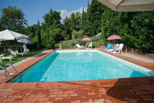 a swimming pool with chairs and umbrellas in a yard at Colle sul Lago in Castiglione del Lago