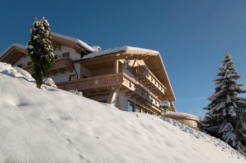 um edifício no topo de uma colina nevada com uma árvore em Residence Garni Melcherhof em Racines