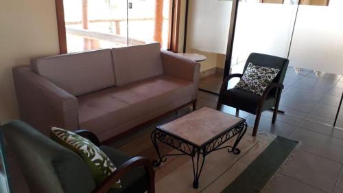 a living room with a couch and a chair at QUINZE HOTEL & POUSADA in Bataguaçu