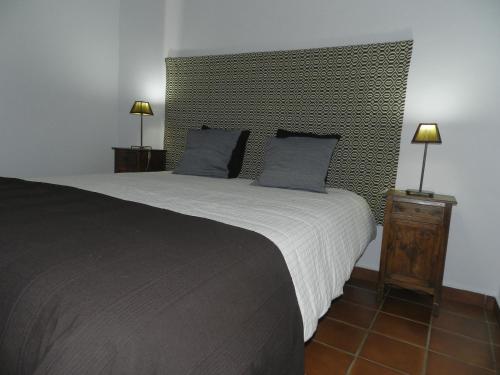 a bedroom with a large bed with two blue pillows at Casas do Ardila in Santo Amador