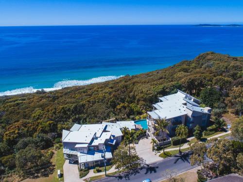 een luchtzicht op een huis op een heuvel naast de oceaan bij Rainbow Ocean Palms Resort in Rainbow Beach