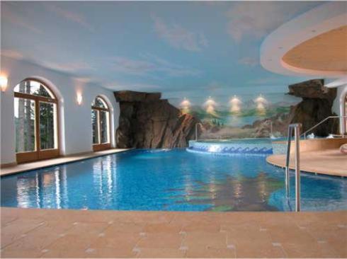 a swimming pool in a hotel with a painting on the wall at Hotel Fior Di Bosco in Giovo