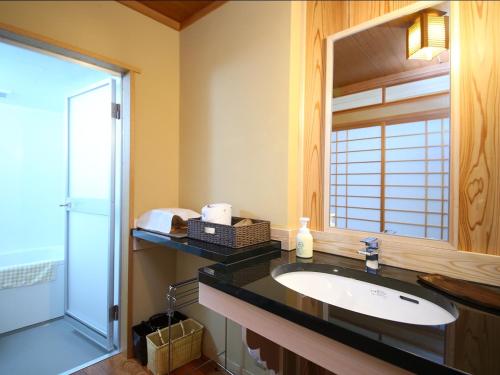 ein Bad mit einem Waschbecken und einem Spiegel in der Unterkunft Kamei no Yu in Yamanouchi