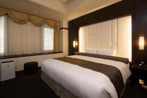 a bedroom with a large bed and two windows at Sapporo Grand Hotel in Sapporo