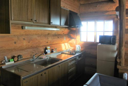 a kitchen with a sink and a refrigerator at White Tree Log House Madarao Tangram in Shinano