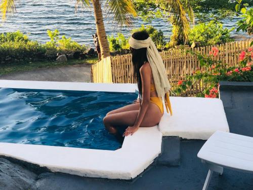 a woman sitting on a bench next to a swimming pool at Bintana Sa Paraiso in Mambajao