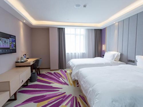 a hotel room with two beds and a desk at Lavande Hotel (Yongxin Bubugao Times Square) in Yongxin
