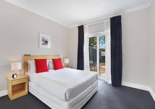 a bedroom with a large white bed with red pillows at Sydney Airport Suites in Sydney