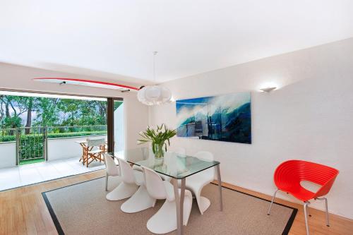 a dining room with a glass table and red chairs at 1/18 Allambi Rise in Noosa Heads
