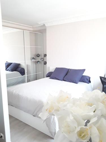 - une chambre dotée d'un lit avec des draps blancs et des fleurs dans l'établissement Apartment with Car Park - Bastille Neighborhood, à Paris