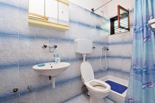 W wyłożonej niebieskimi kafelkami łazience znajduje się toaleta i umywalka. w obiekcie Apartment and Rooms Mila w mieście Seline