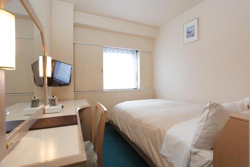 a hotel room with a bed and a desk with a television at Aizuwakamatsu Washington Hotel in Aizuwakamatsu