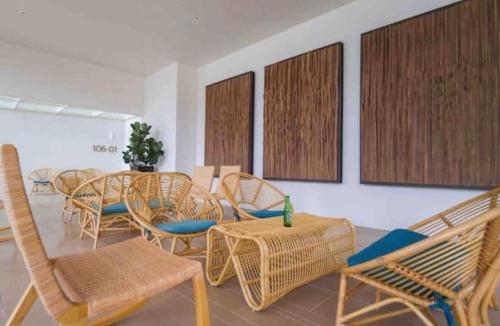 a room with wicker chairs and tables and chairs at By The Sea Beach Front Apartment in Batu Ferringhi