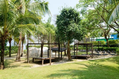 a group of benches in a park with palm trees at By The Sea Beach Front Apartment in Batu Ferringhi