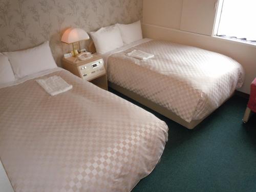 a hotel room with two beds and a window at Aizuwakamatsu Washington Hotel in Aizuwakamatsu