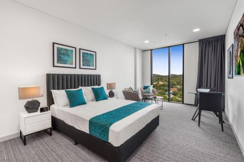 a bedroom with a king sized bed and a desk at Essence Suites Taringa in Brisbane