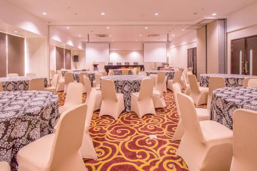 a banquet hall with tables and white chairs at Mercure Pontianak City Center in Pontianak