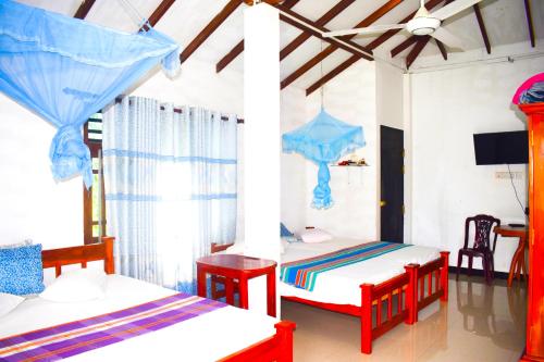 a bedroom with two beds and a tv in it at Hotel Birds View in Tissamaharama
