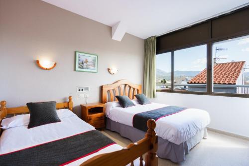 two beds in a room with a window at Hotel Costa Andaluza in Motril