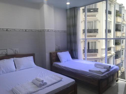 a bedroom with two beds and a large window at Hotel thanh vinh in Ho Chi Minh City