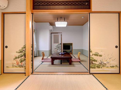 a living room with a table and a glass door at Ryokan Niko in Koganei
