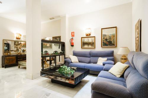 una sala de estar con sofás azules y una mesa. en Hotel Costa Andaluza en Motril