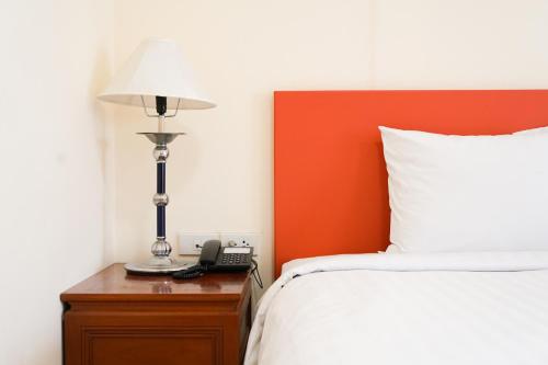 a bedroom with a bed and a lamp on a night stand at White House Bizotel in Bangkok