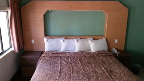 a bedroom with a bed with white pillows and a green wall at HOTEL AZTECA INN in Ensenada