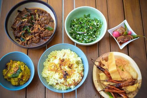 a table with four bowls of different types of food at Monara Backpacker Inn Unawatuna in Unawatuna