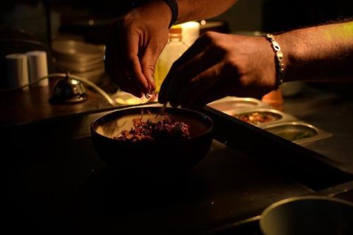 a person preparing a bowl of food on a counter at Monara Backpacker Inn Unawatuna in Unawatuna