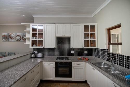 a kitchen with white cabinets and a stove top oven at Nkomazi Kruger Lodge & Spa in Malelane