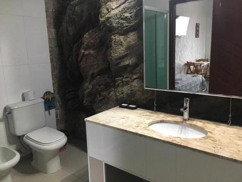 a bathroom with a toilet and a sink and a mirror at Pousada Casa Atlântica in Angra dos Reis