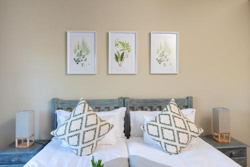 a bedroom with a bed with four pictures on the wall at Nkomazi Kruger Lodge & Spa in Malelane