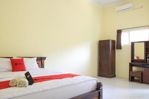 a bedroom with a bed with red pillows and a mirror at RedDoorz Syariah near Balai Kota Probolinggo 2 in Probolinggo