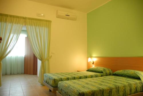 a hotel room with two beds and a window at B&B Cristina in Torricella