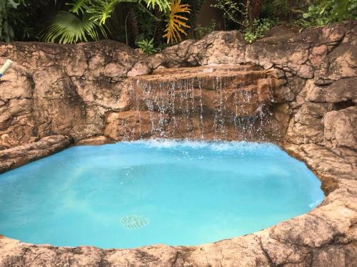 une grande piscine avec une cascade dans un mur en pierre dans l'établissement Tranquility, à Margate