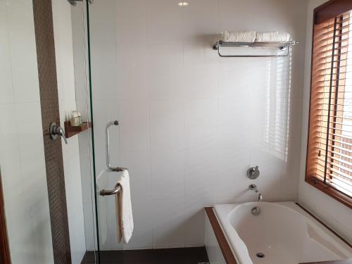 a white bathroom with a bath tub and a window at Le Palais Juliana in Luang Prabang