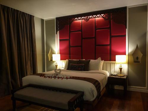 a hotel room with a large bed with a red headboard at Le Palais Juliana in Luang Prabang