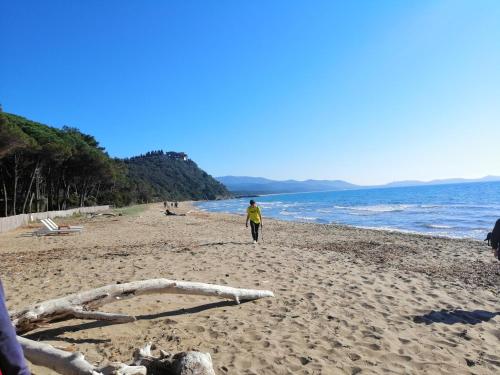 a man walking on a beach next to the ocean at Agriturismo Bocci in Castiglione della Pescaia
