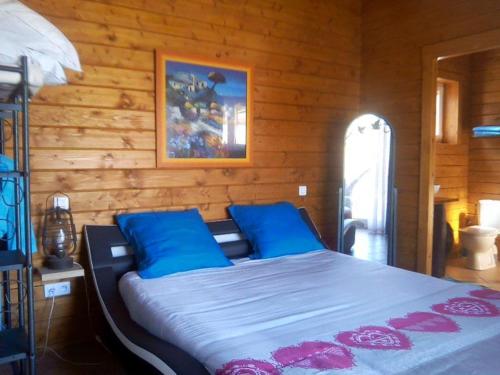 1 cama con almohadas azules en una habitación de madera en Les Hauts du Clos 645 le Rayol, en Correns